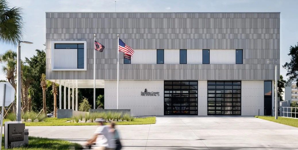 Modern building with garage doors, flags, and a blurred person on a bike.