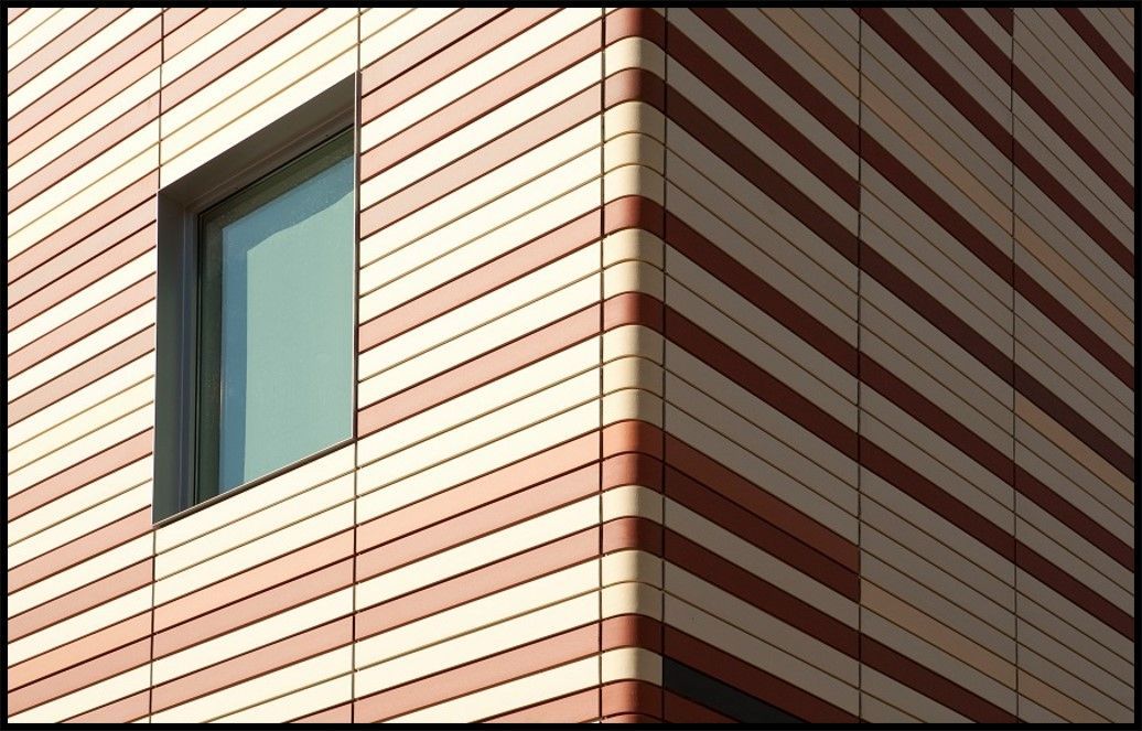 Corner of a building with horizontally striped red and cream facade and a rectangular window.