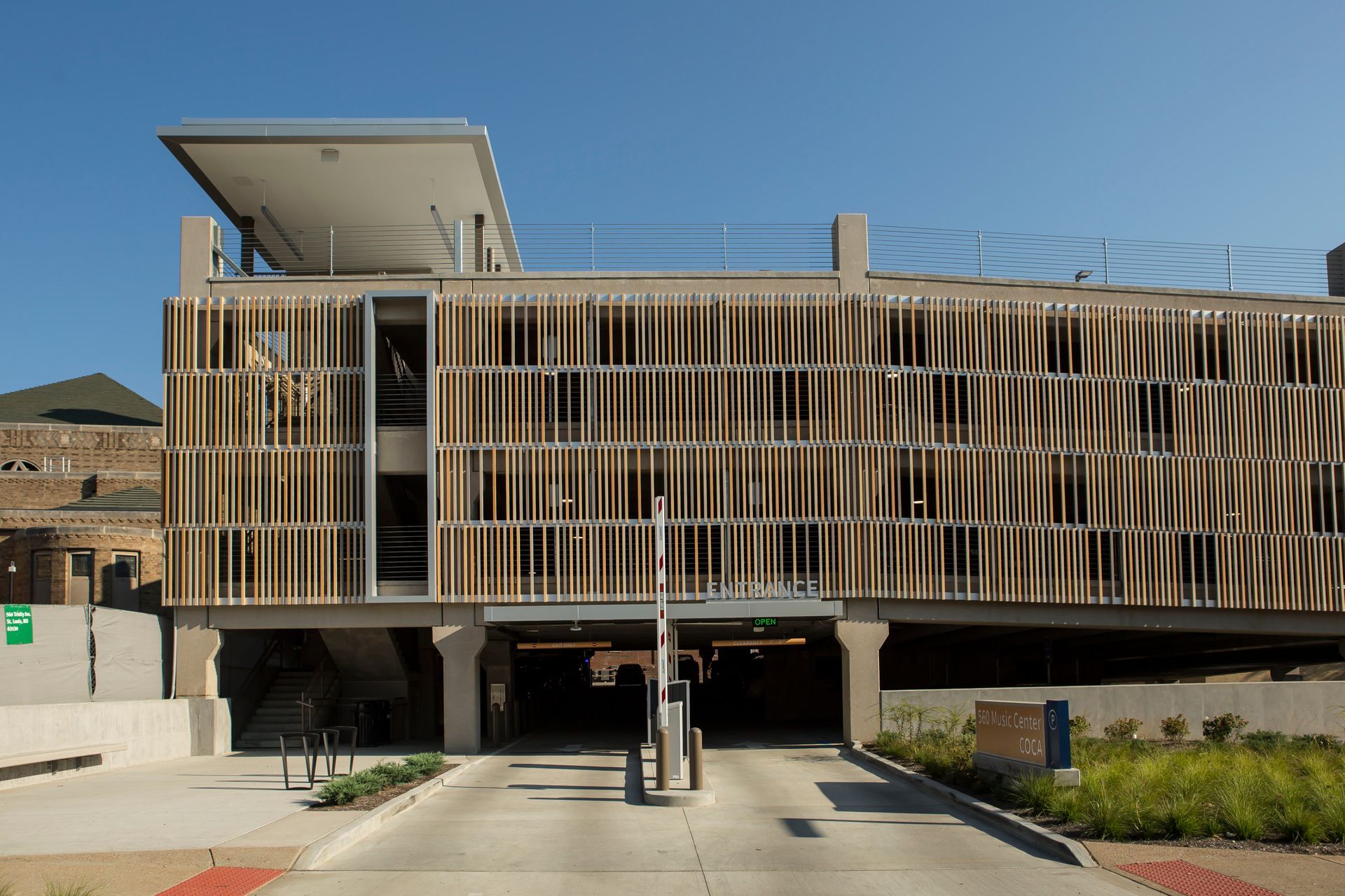 Parking garage entrance with beige slat facade under a clear blue sky.