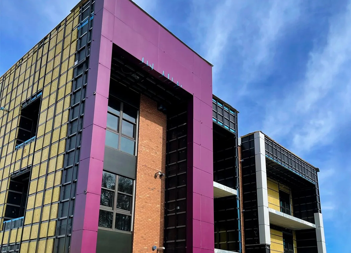 Modern building with purple and yellow facade under a blue sky.