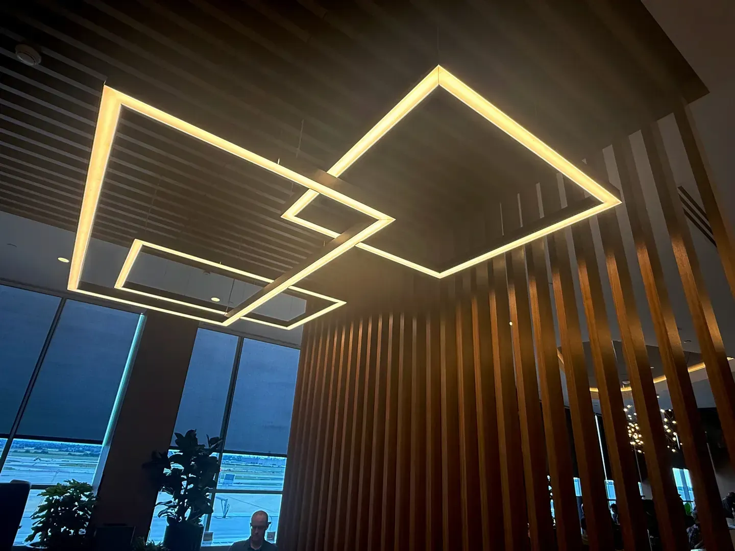 Modern interior with geometric pendant lights and wooden slat wall.