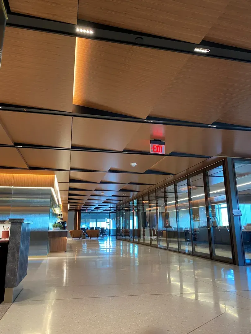 Long hallway with wood ceiling panels, glass walls, and a visible 