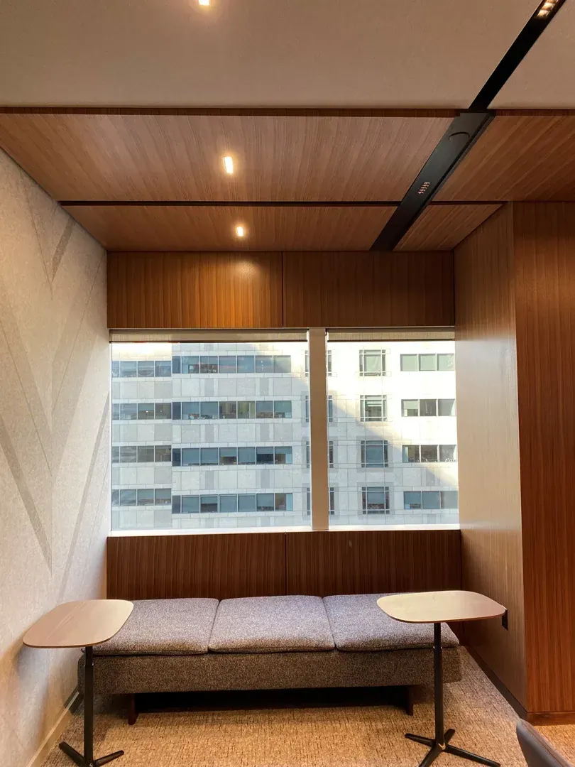 Cozy office nook with bench seating, small tables, window, and wood paneling.