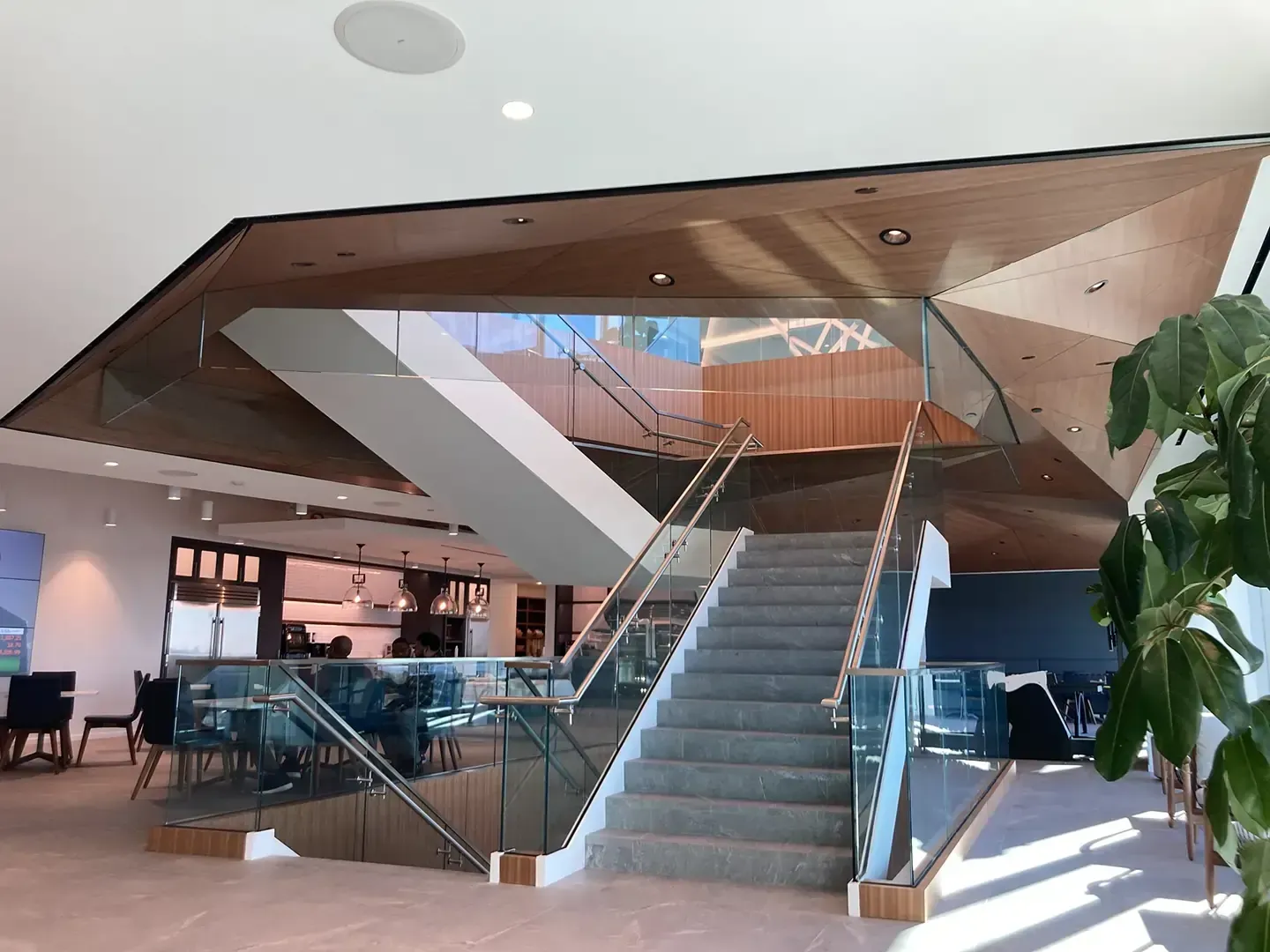 Staircase with glass railings and wood accents. A light-filled open space.