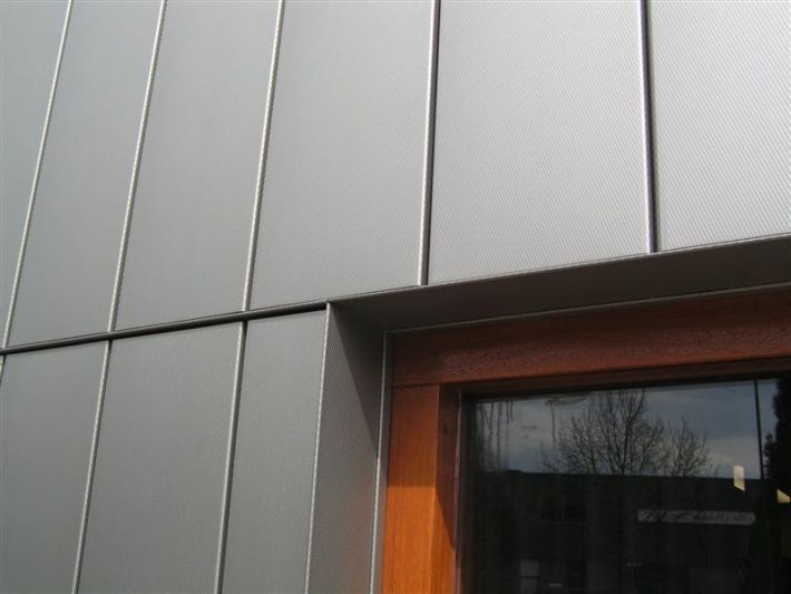 Gray metal building panels with a brown-framed window.