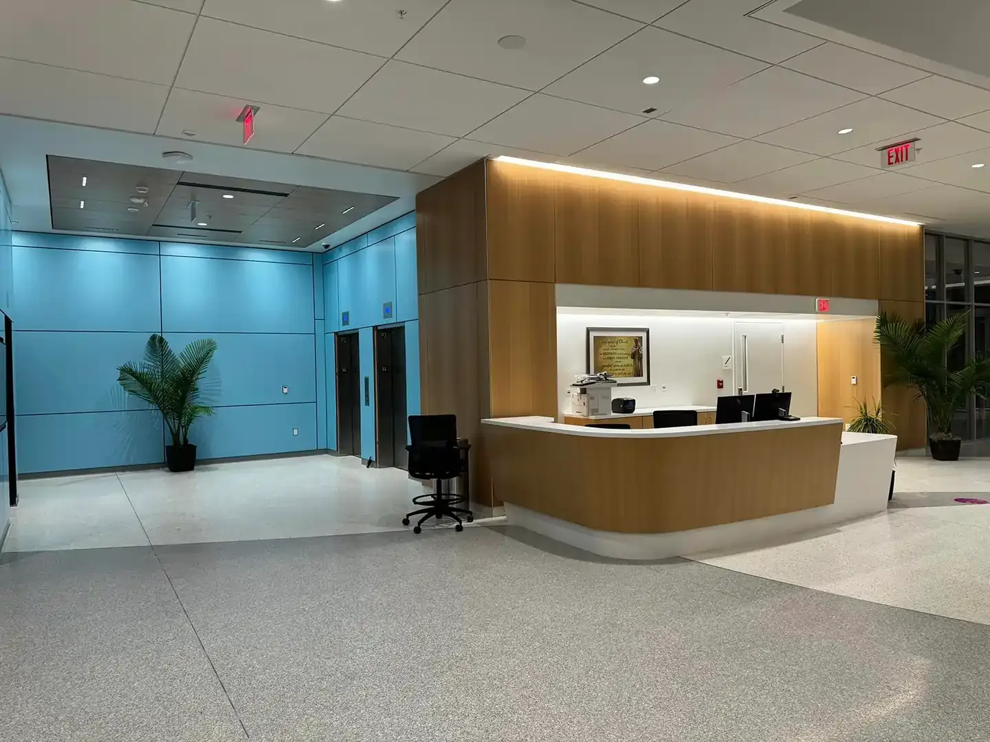 Elevator lobby with a reception desk, light blue wall panels, and terrazzo flooring.