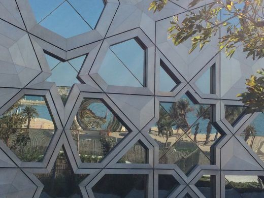 Geometric facade with window reflections of a beach and palm trees.