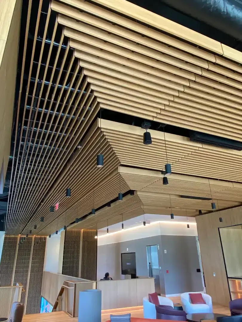 Wooden slatted ceiling with recessed lighting; lobby with seating and stairs.