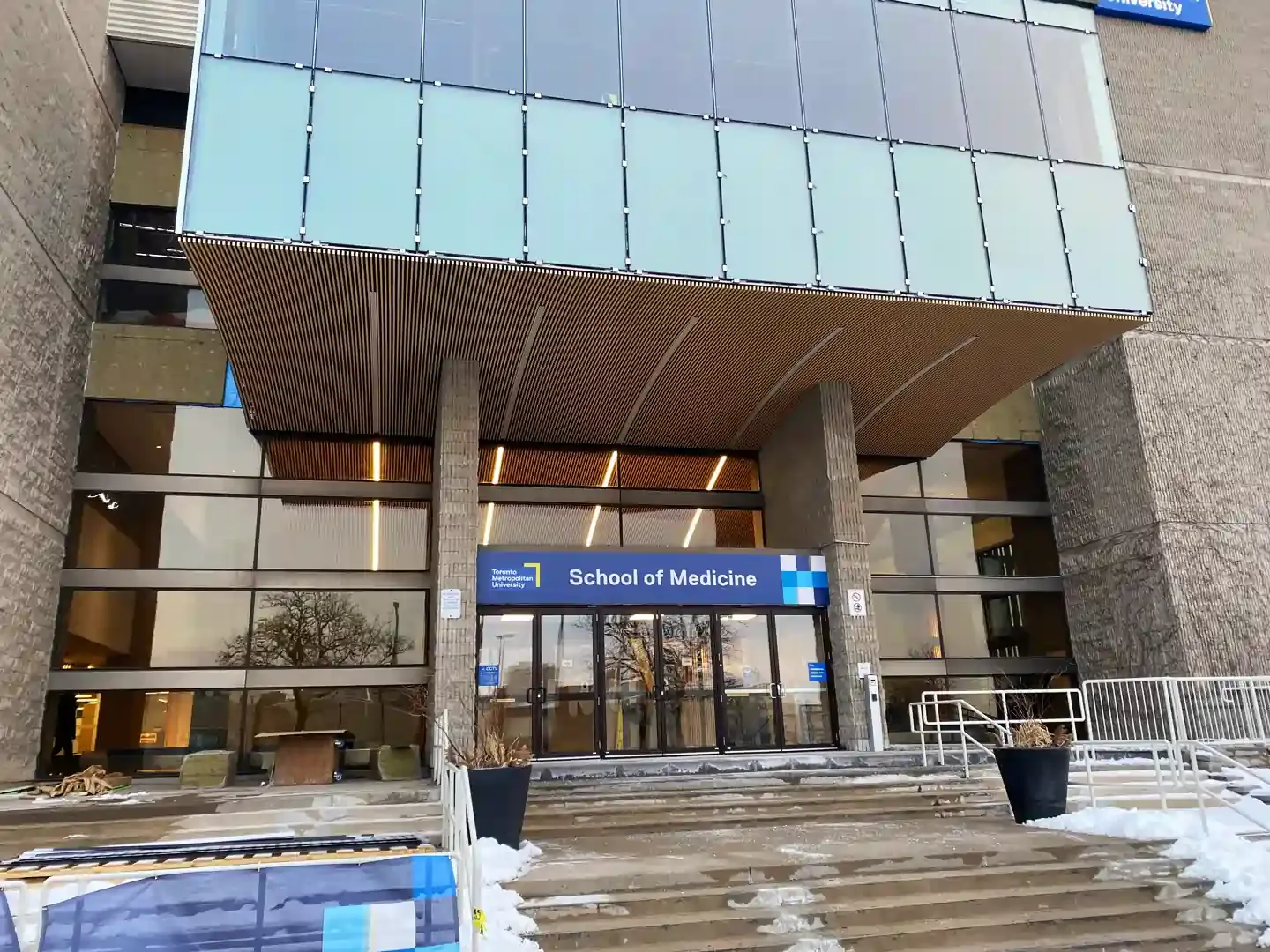 Entrance to the Colonial Inn building. Glass doors under a patterned overhang. Steps lead up to the entrance.
