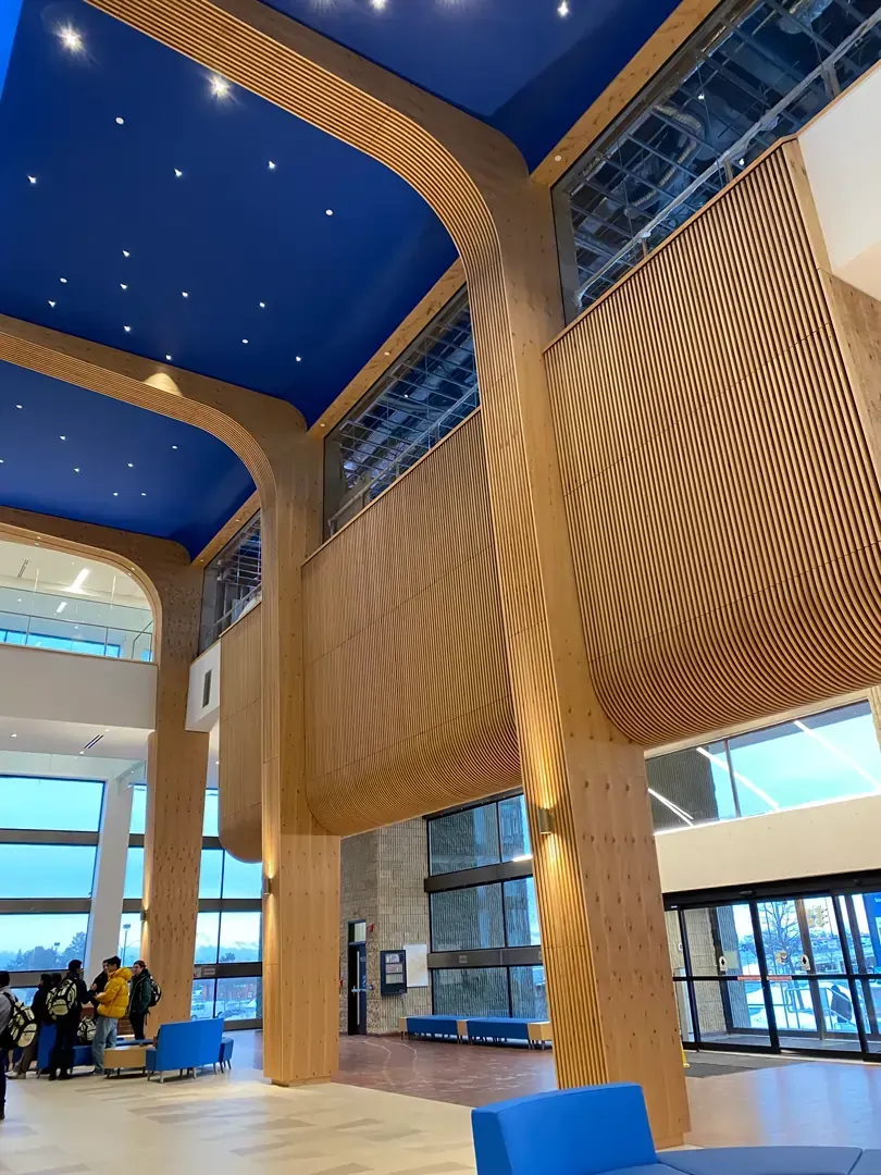 Large wooden architectural structure in a building interior, with blue ceiling and windows.