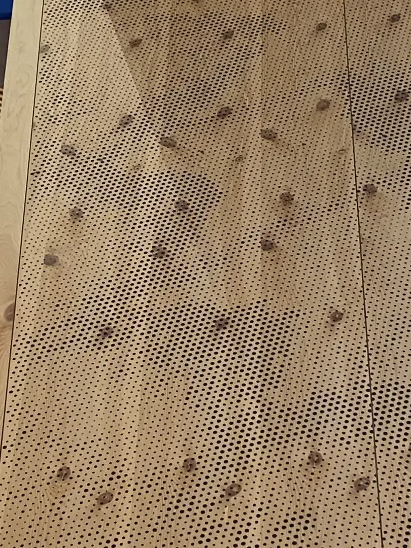 Tan perforated panels with dark spots arranged in a grid pattern.