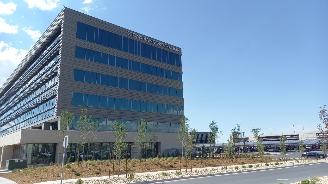 Modern office building with many windows under a blue sky.