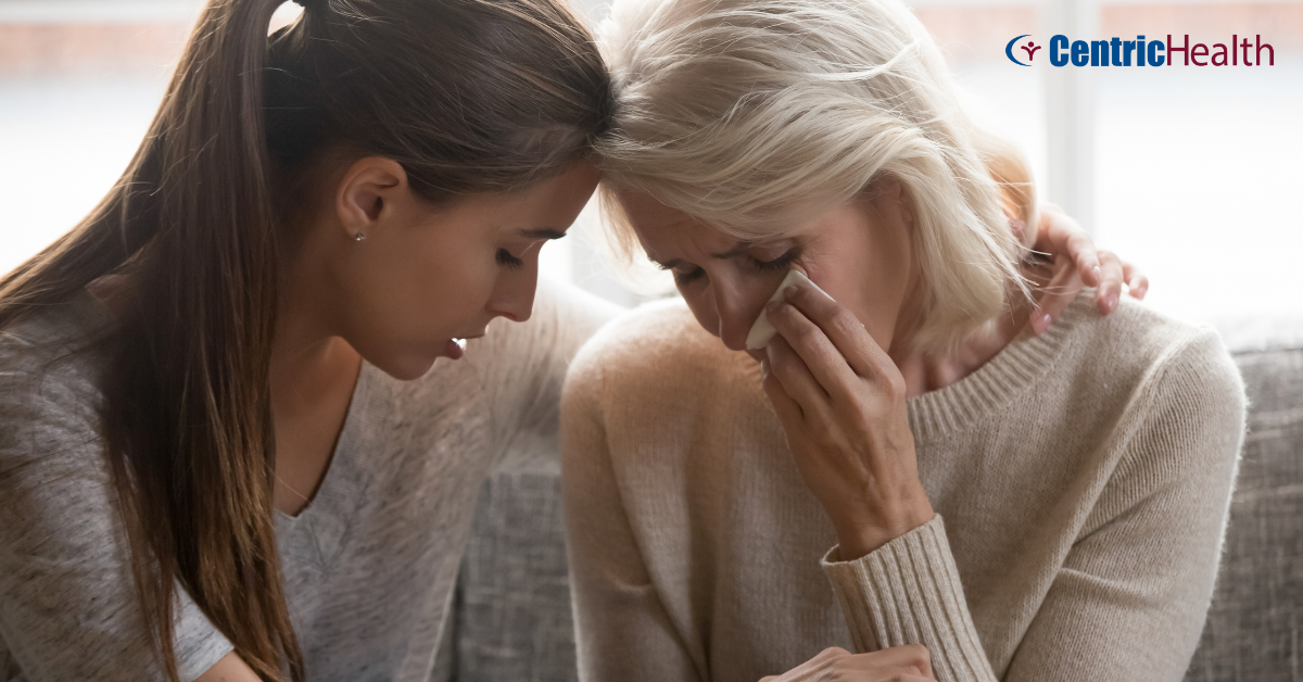 young female offering comfort to a mother figure who is crying