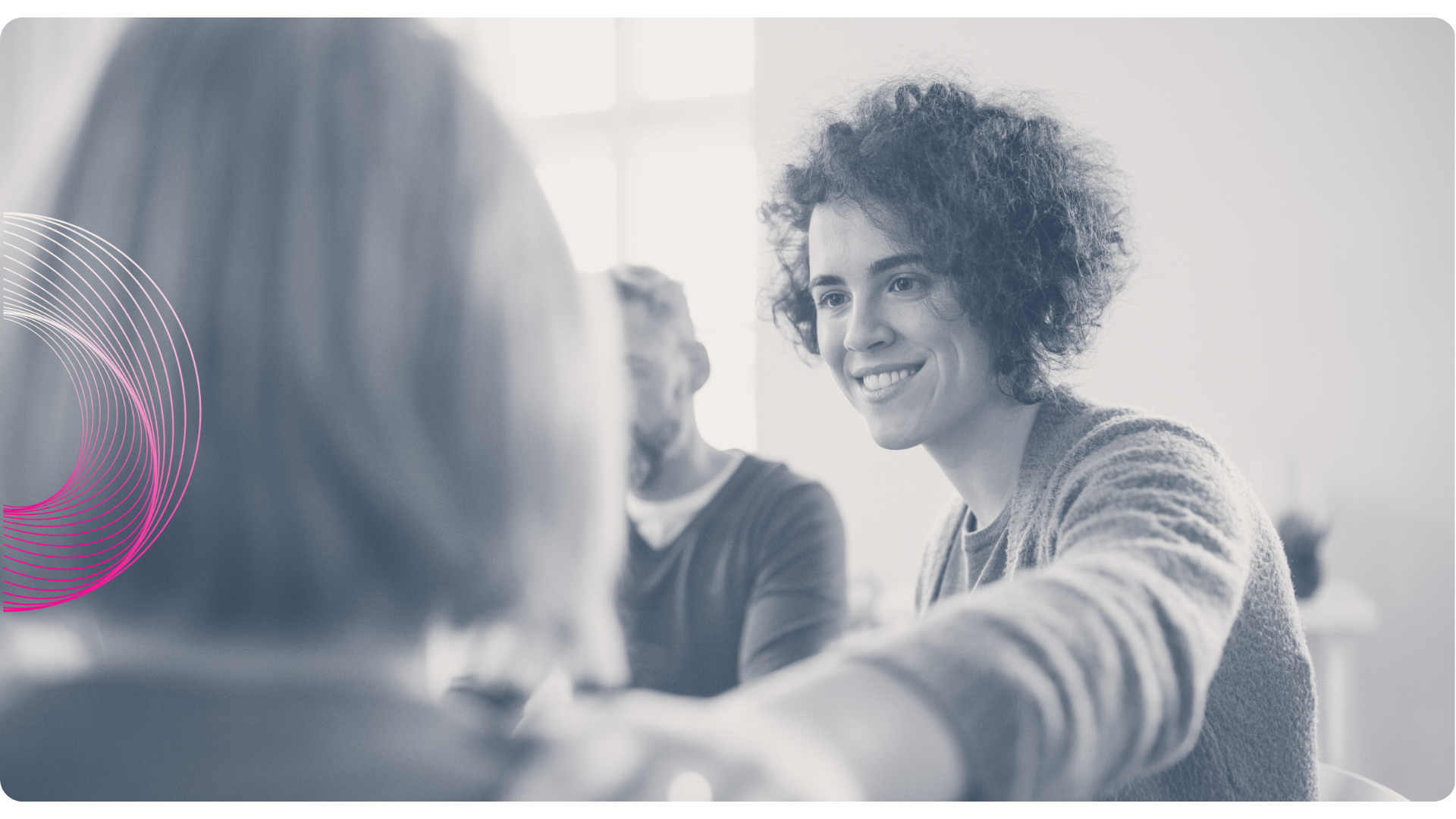 Person smiles, hand on shoulder of another; group meeting.
