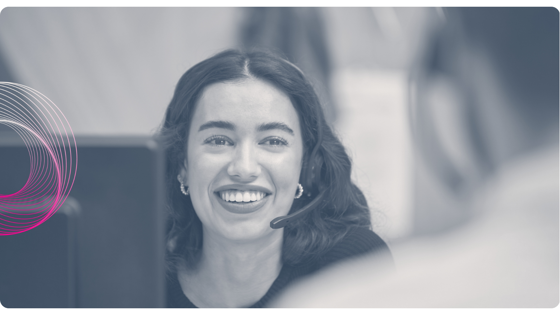 Woman wearing a headset smiles while looking at someone off-camera, possibly in an office setting.