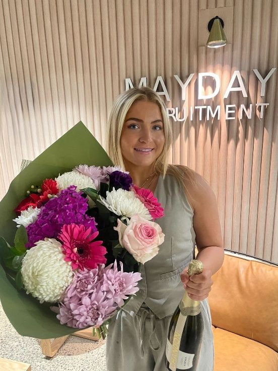 Woman holding flowers and champagne in front of 