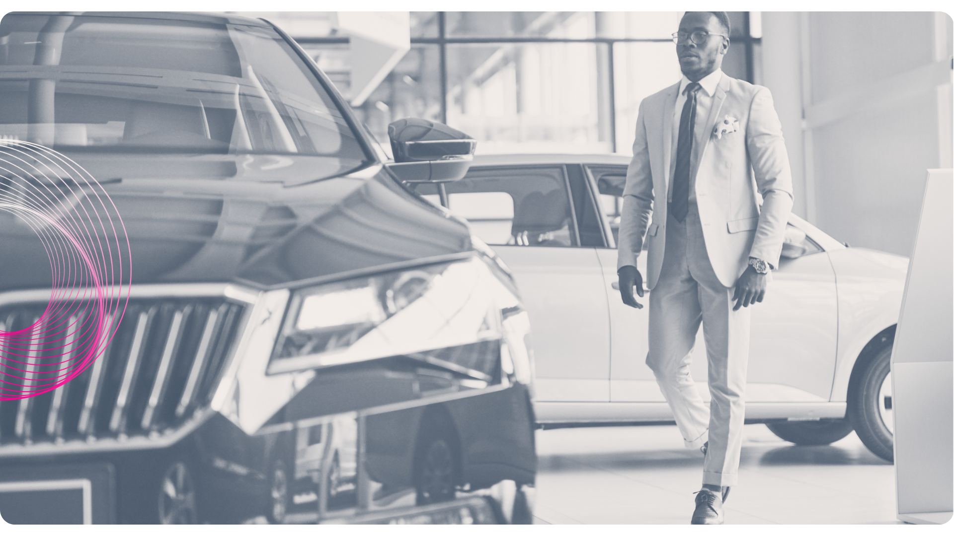 Man in suit walking in a car showroom, cars in background.