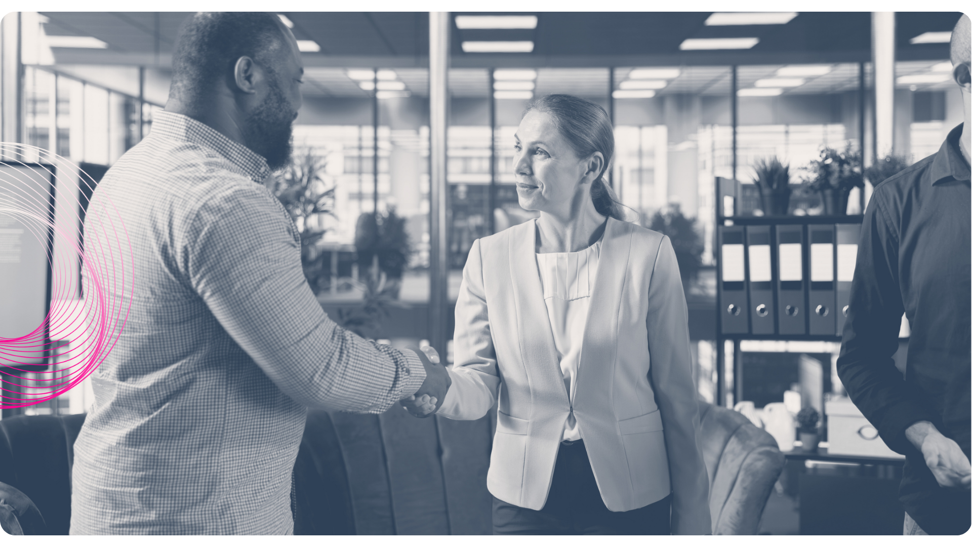 Person shaking hands in an office, other person present. Interior with plants and shelving.