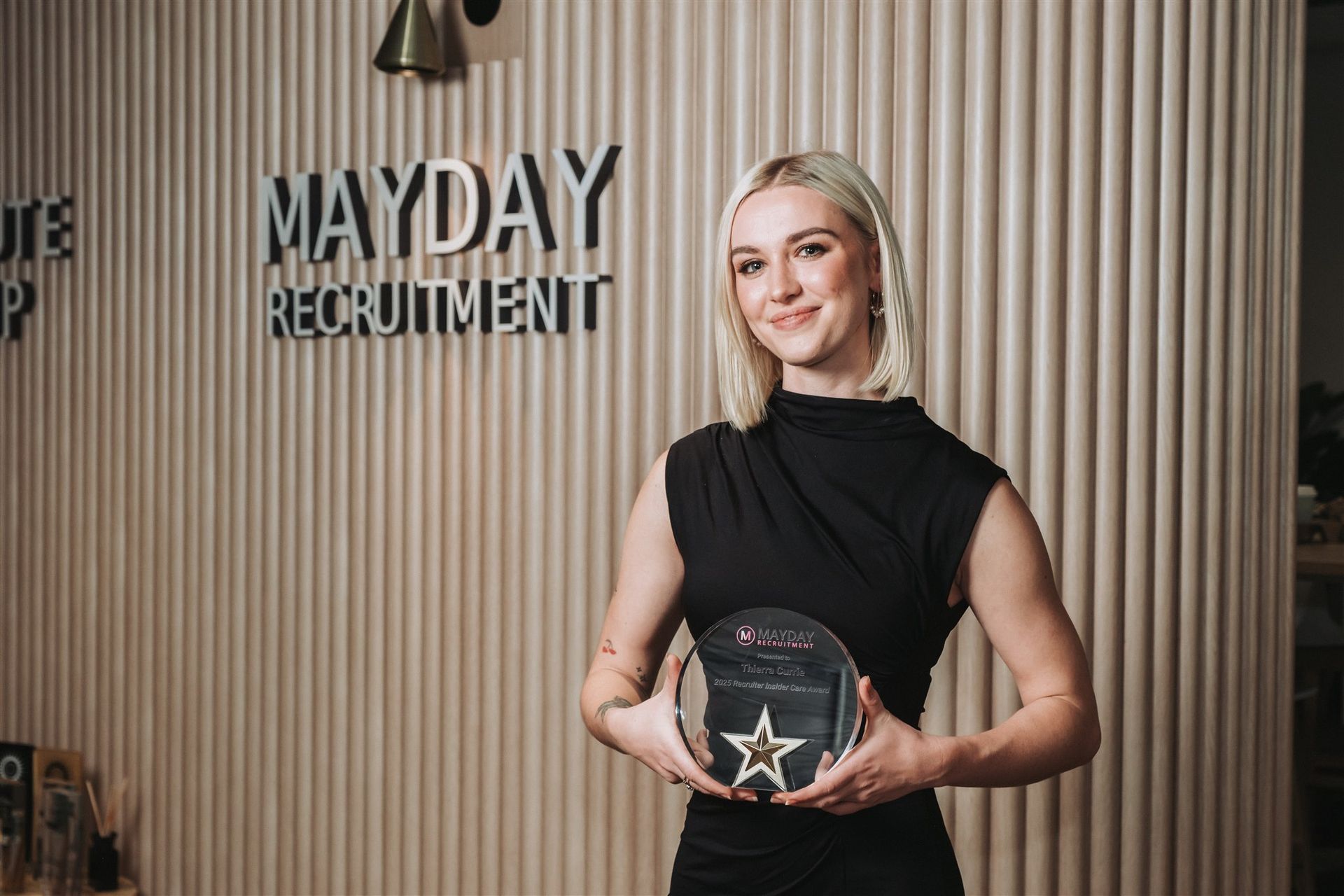 Woman with blonde hair holding an award in front of the