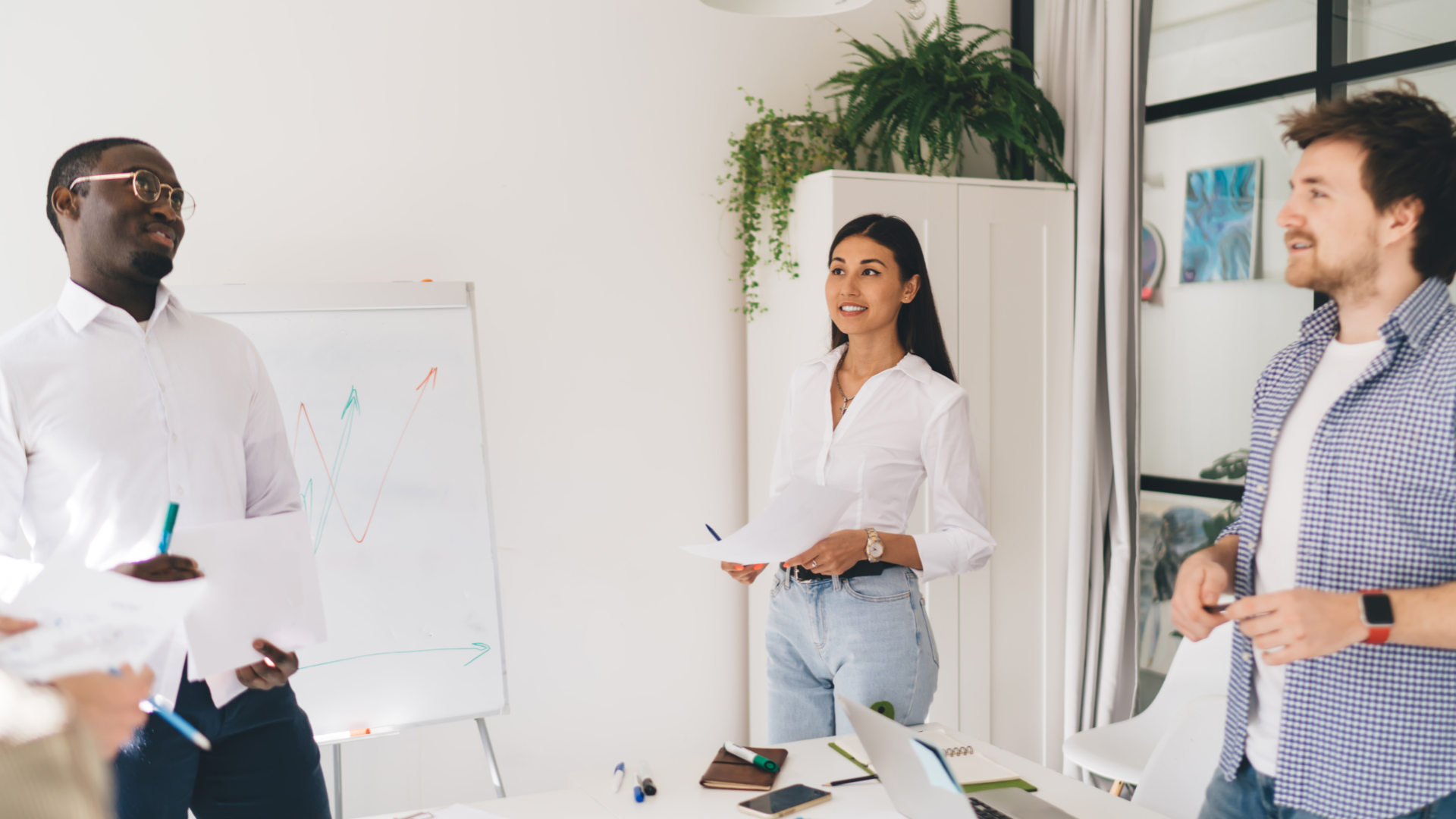 Two men in suits smiling, one signing a document at a desk with a laptop and coffee cup.