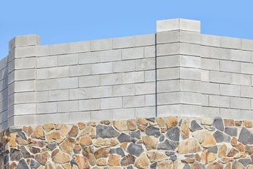 Stone and concrete block wall against a blue sky.