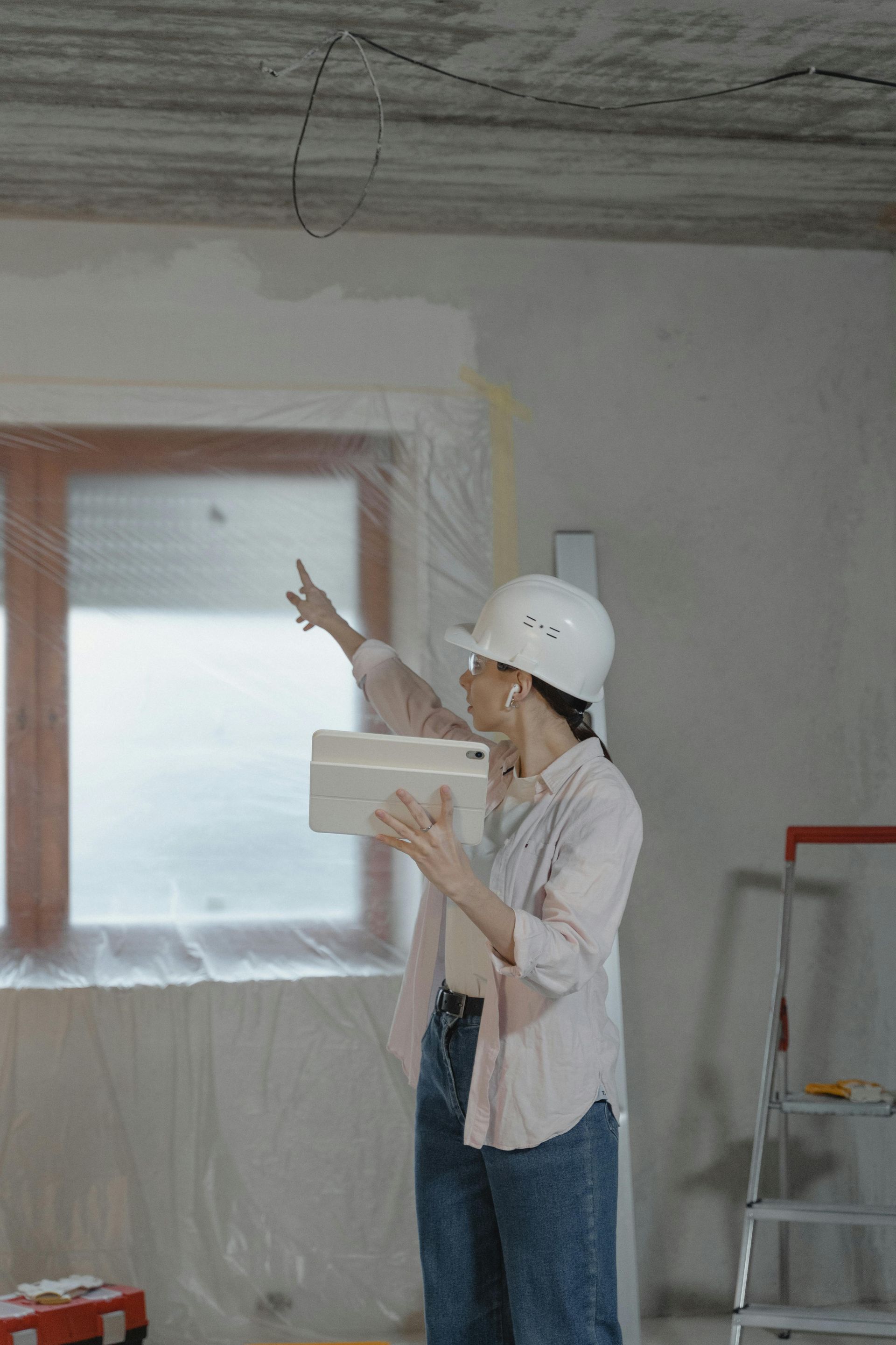 Three people in hard hats reviewing blueprints in a white room.