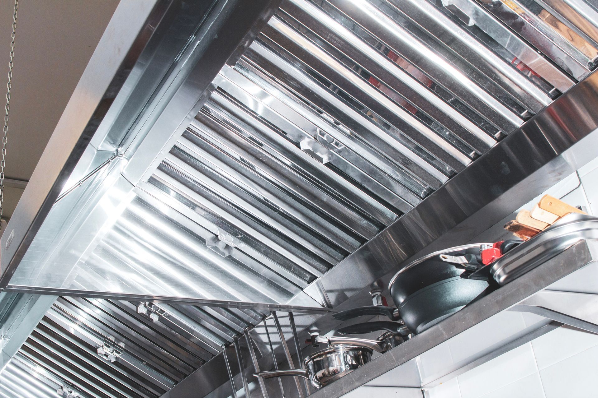A close-up of a professional hood in a restaurant kitchen made of stainless steel. A close-up of a professional hood in a restaurant kitchen made of stainless steel.