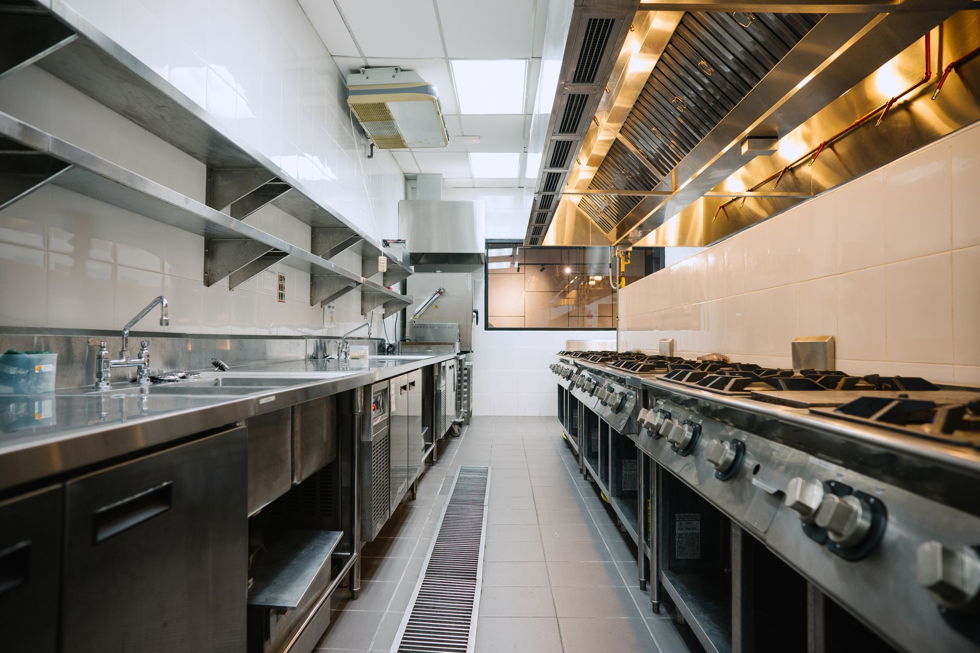 Commercial kitchen with stainless steel counters and multiple gas stoves.