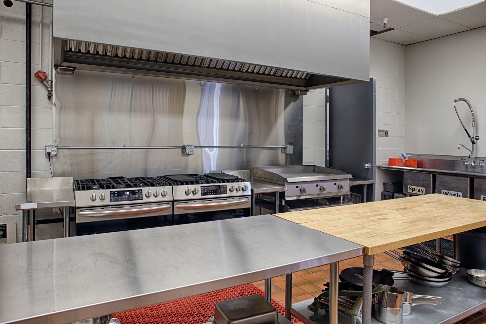 Commercial kitchen with stainless steel stove, oven, and prep tables. Commercial kitchen with stainless steel stove, oven, and prep tables.