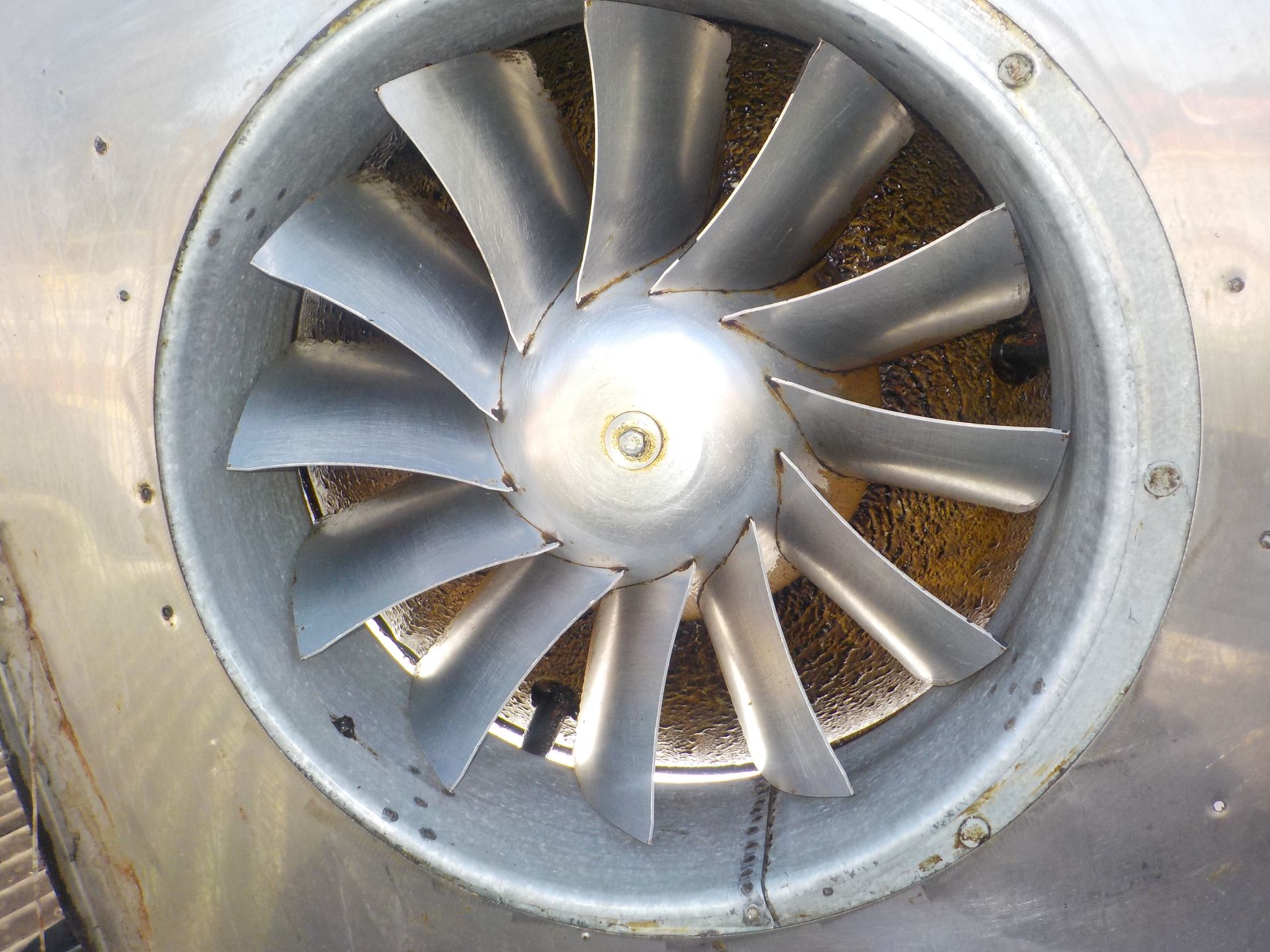 Fan with curved blades inside a silver metal casing, possibly part of an engine.