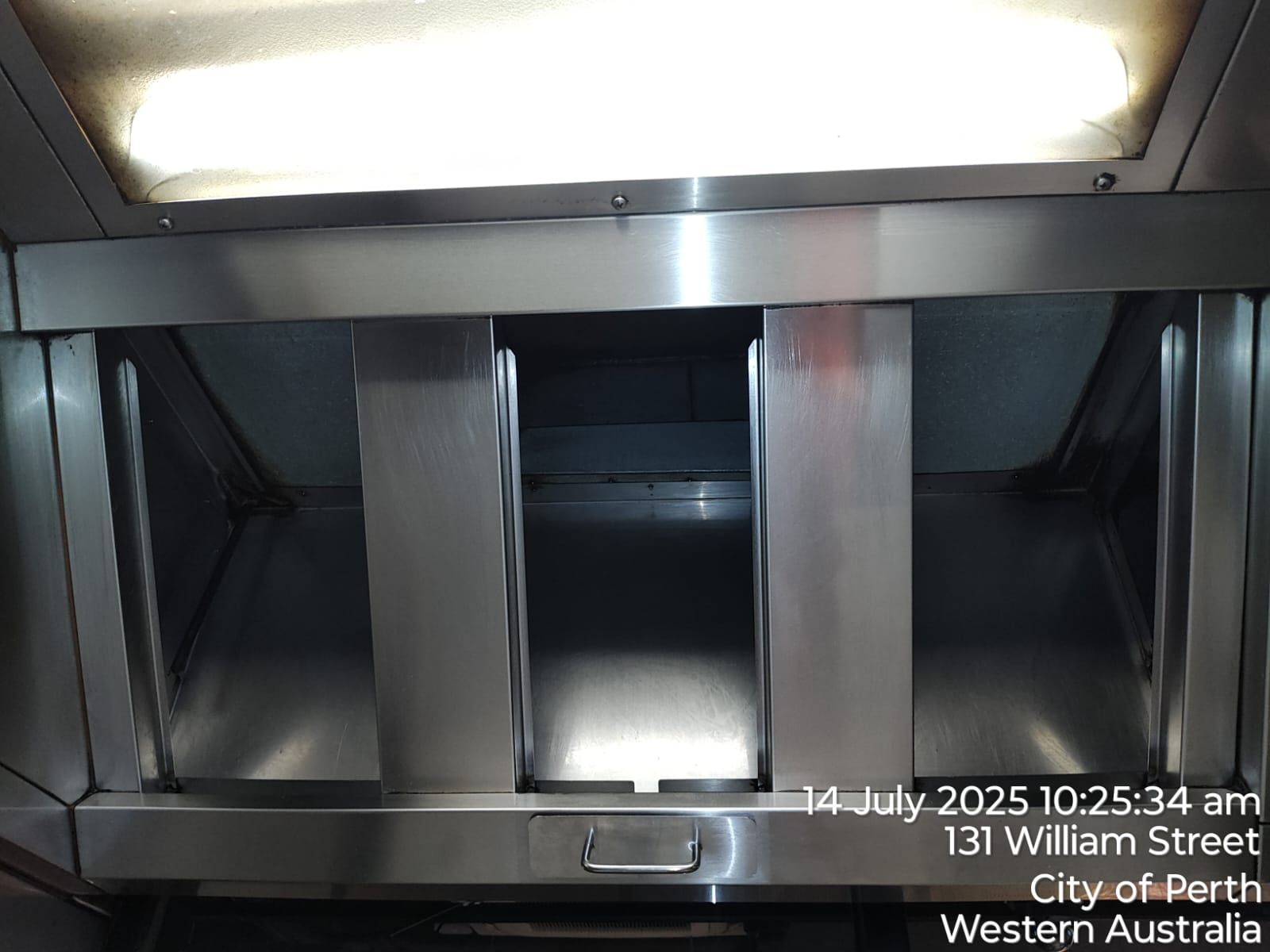 Stainless steel commercial kitchen exhaust hood interior.