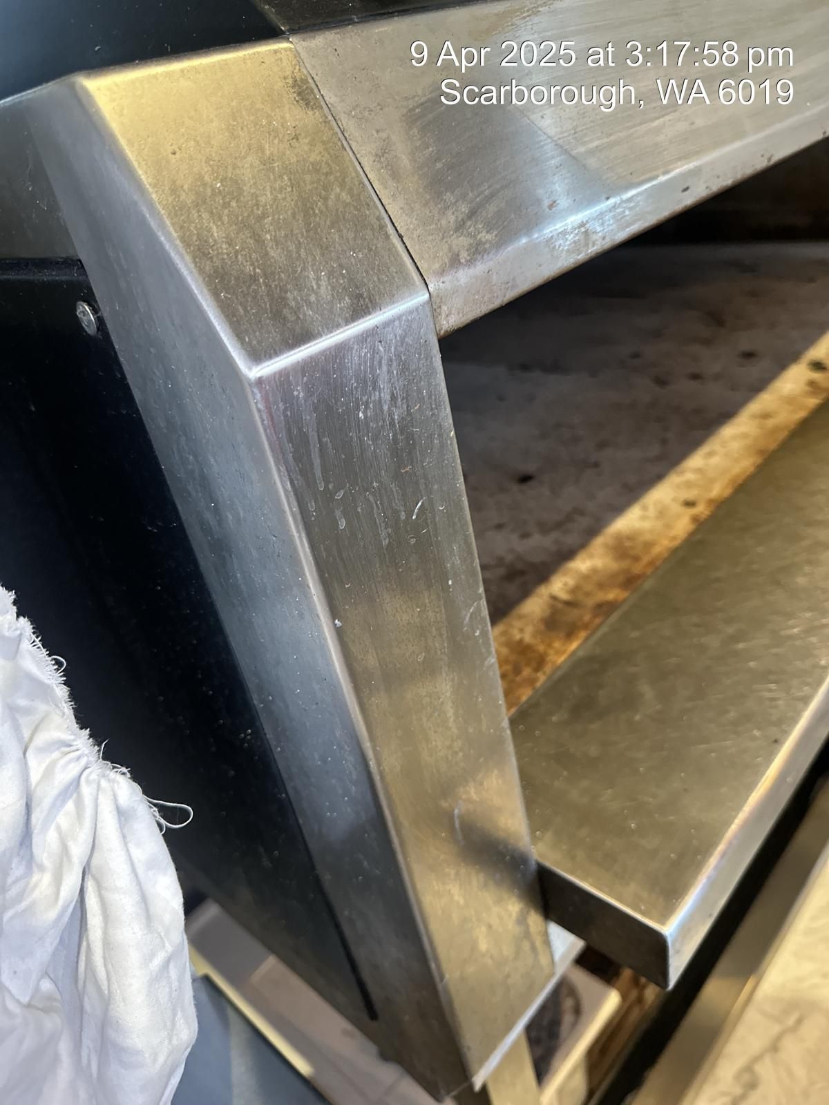 A close up of a stainless steel oven with a person standing next to it.