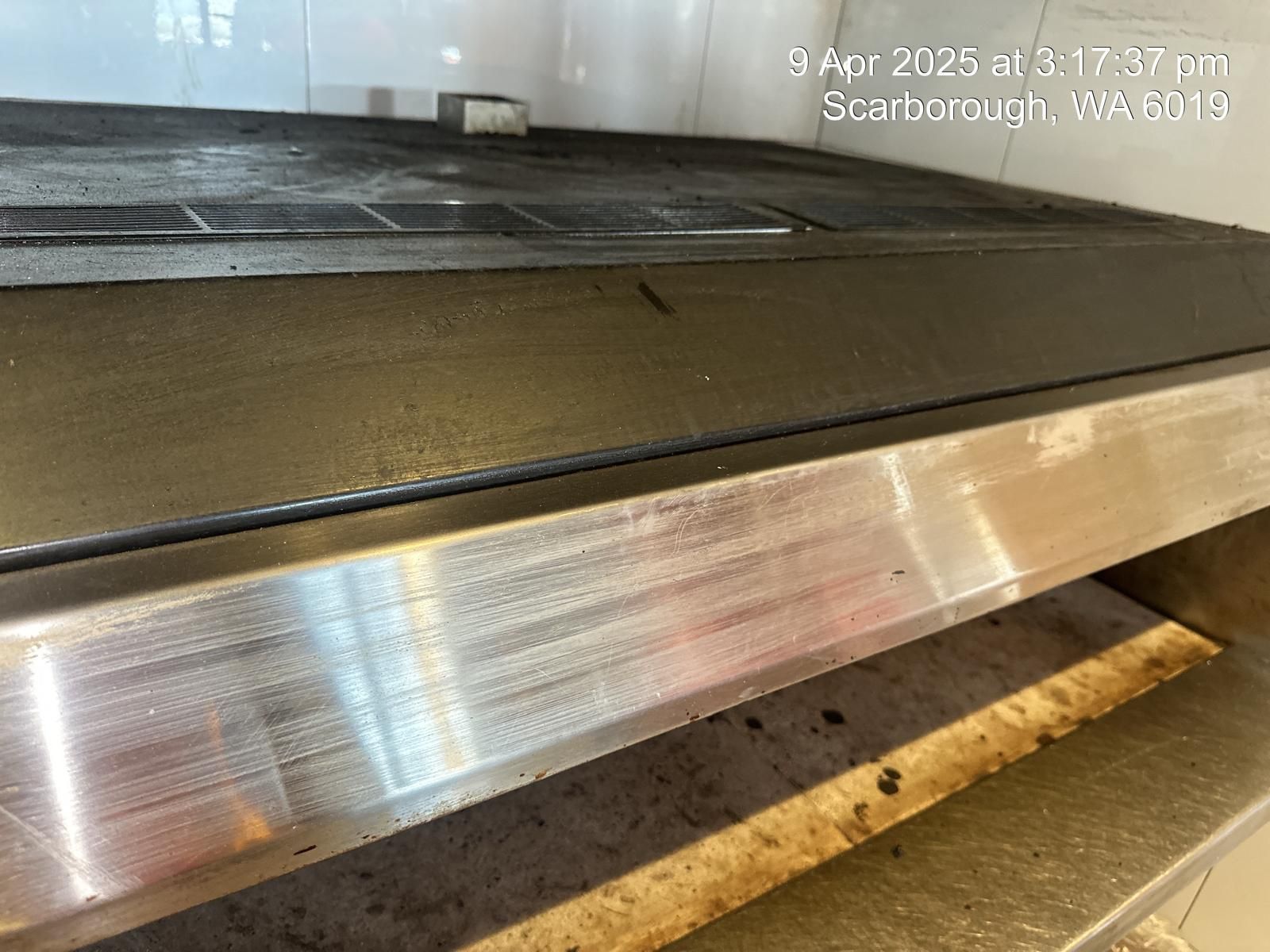 A close up of a stove top oven with a stainless steel shelf.