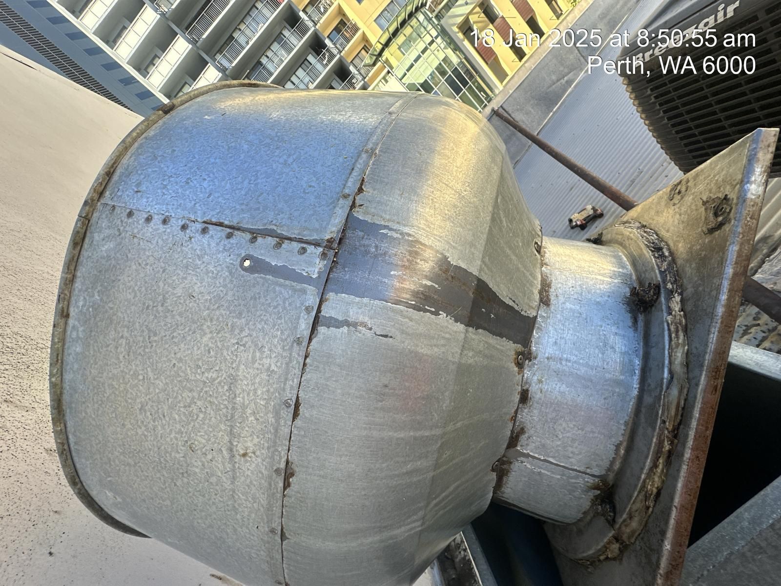 A close up of a metal pipe with a building in the background
