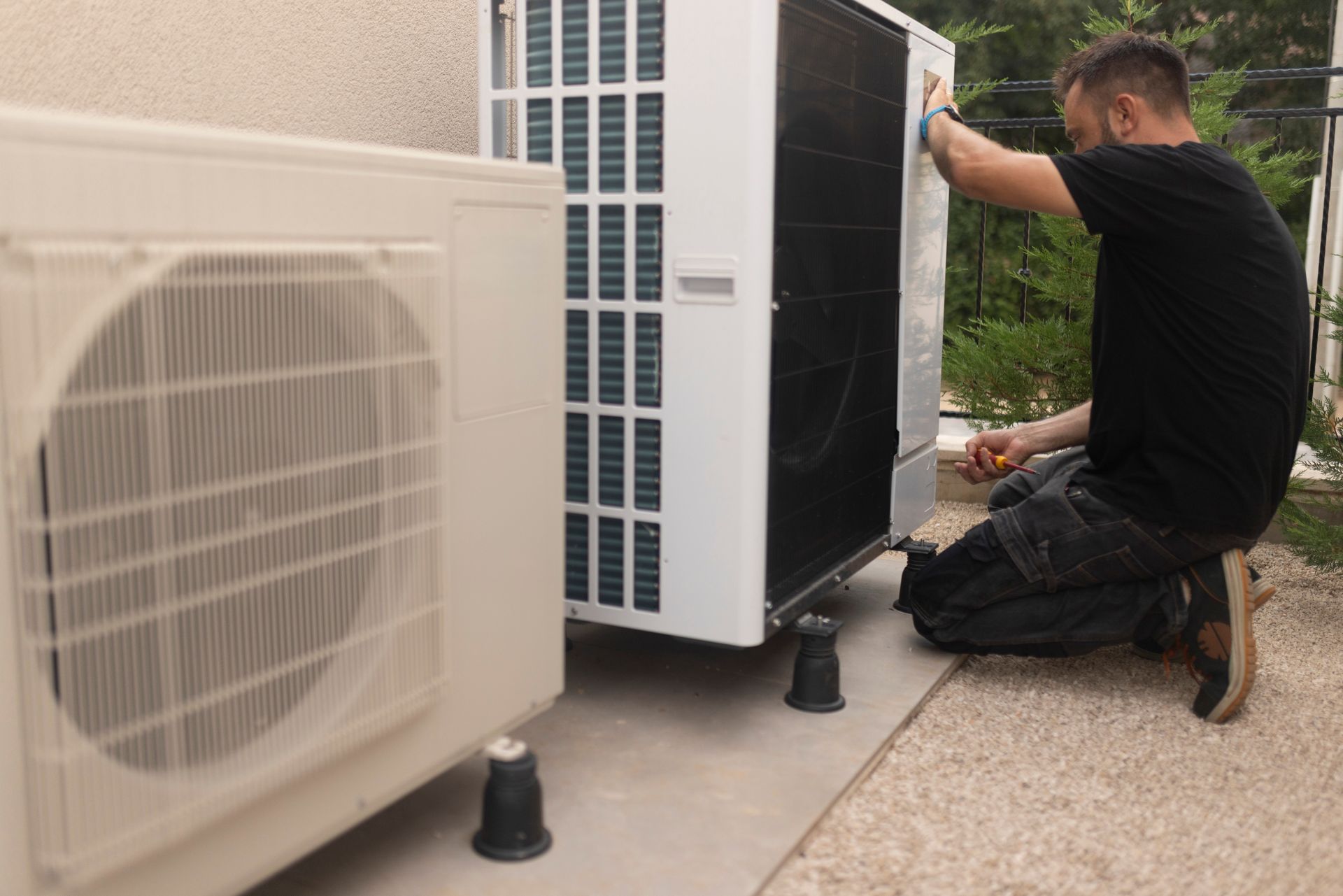 A Man is working on an Air Conditioner outside of a Building - Hialeah, FL - Cajigas Air Conditioning LLC