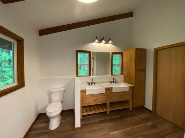 A bathroom with two sinks , a toilet and a mirror.
