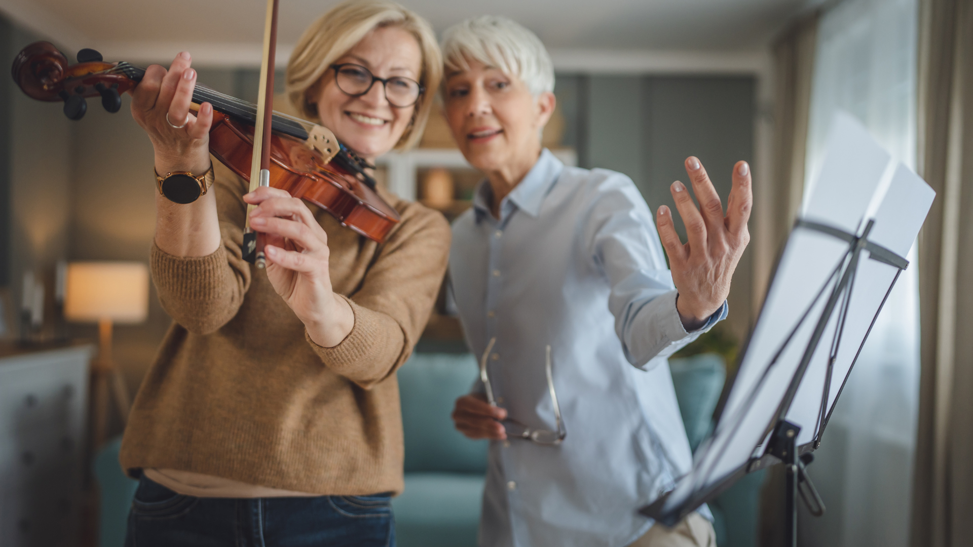 A woman is teaching another woman how to play the violin.
