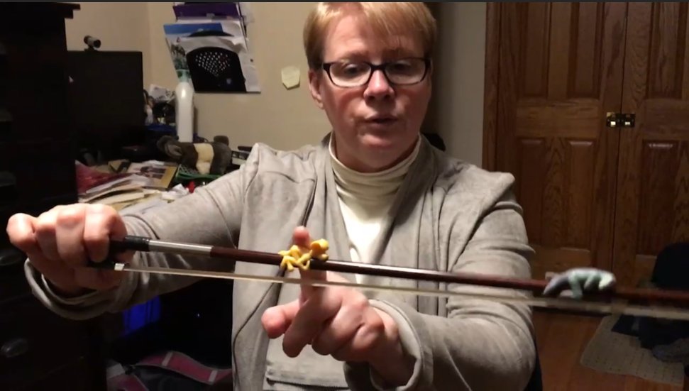 A woman wearing glasses is holding a violin in her hands