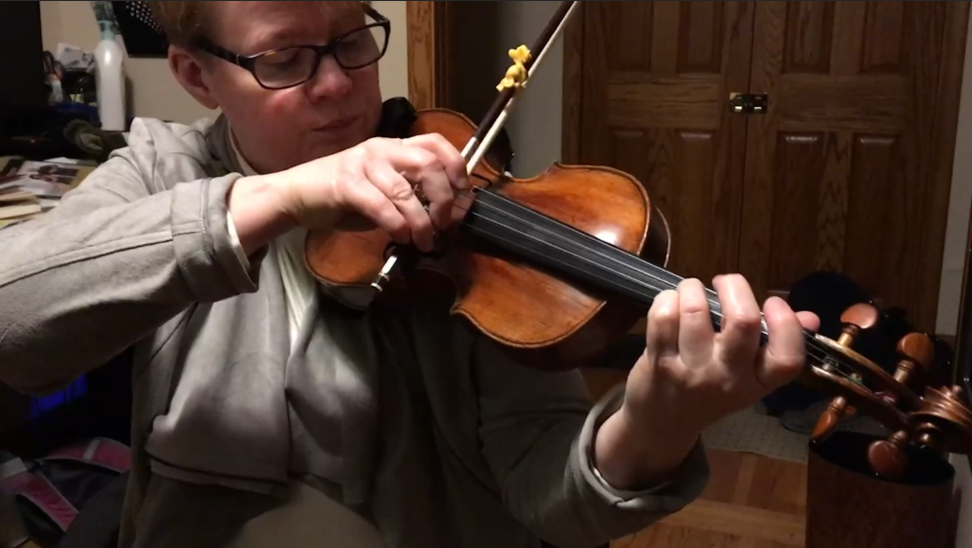 A woman wearing glasses is playing a violin