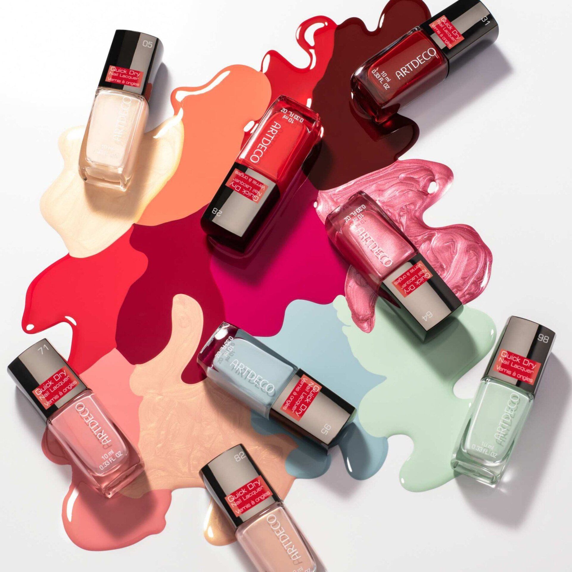 Diverse bottiglie di smalto sono adagiate su una superficie bianca