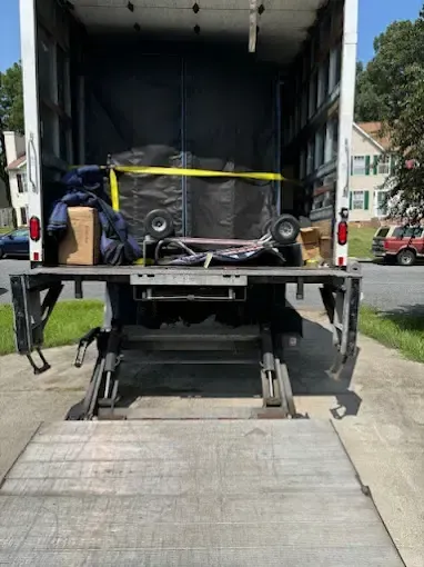 The back of a moving truck is loaded with boxes and speakers.