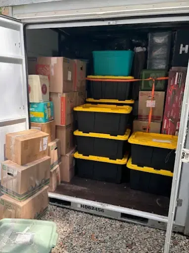 A container filled with boxes and plastic bins.