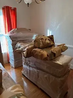 A living room filled with furniture wrapped in plastic.