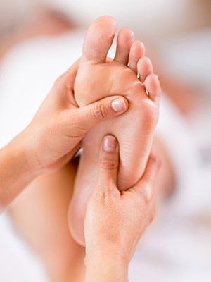 Hands massaging the sole of a foot in close-up, indoors.