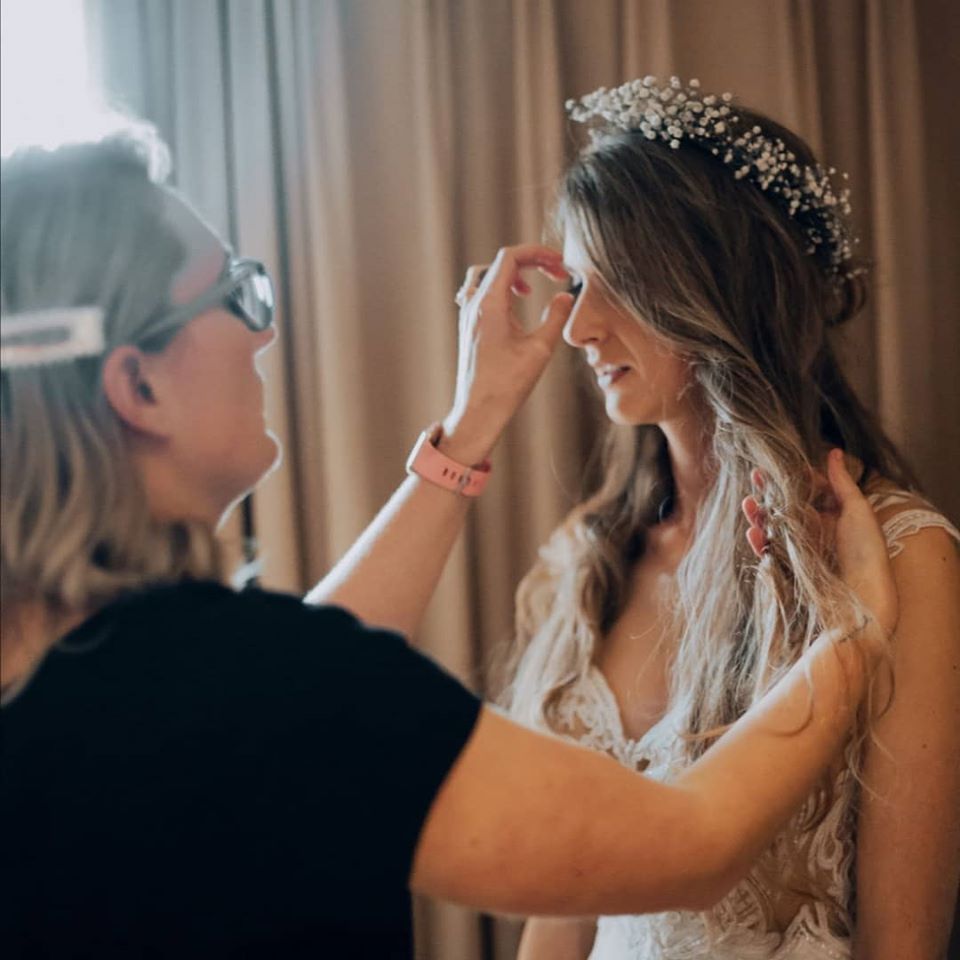 A makeup artist applies finishing touches to a bride's face, as she prepares for her wedding.