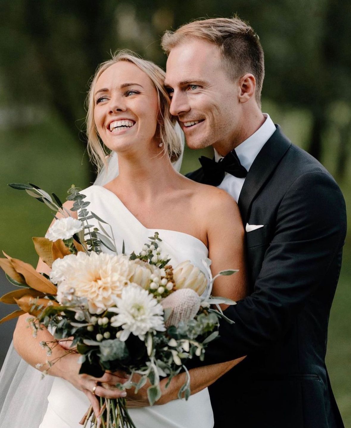 Bride and groom smiling and embracing outdoors.