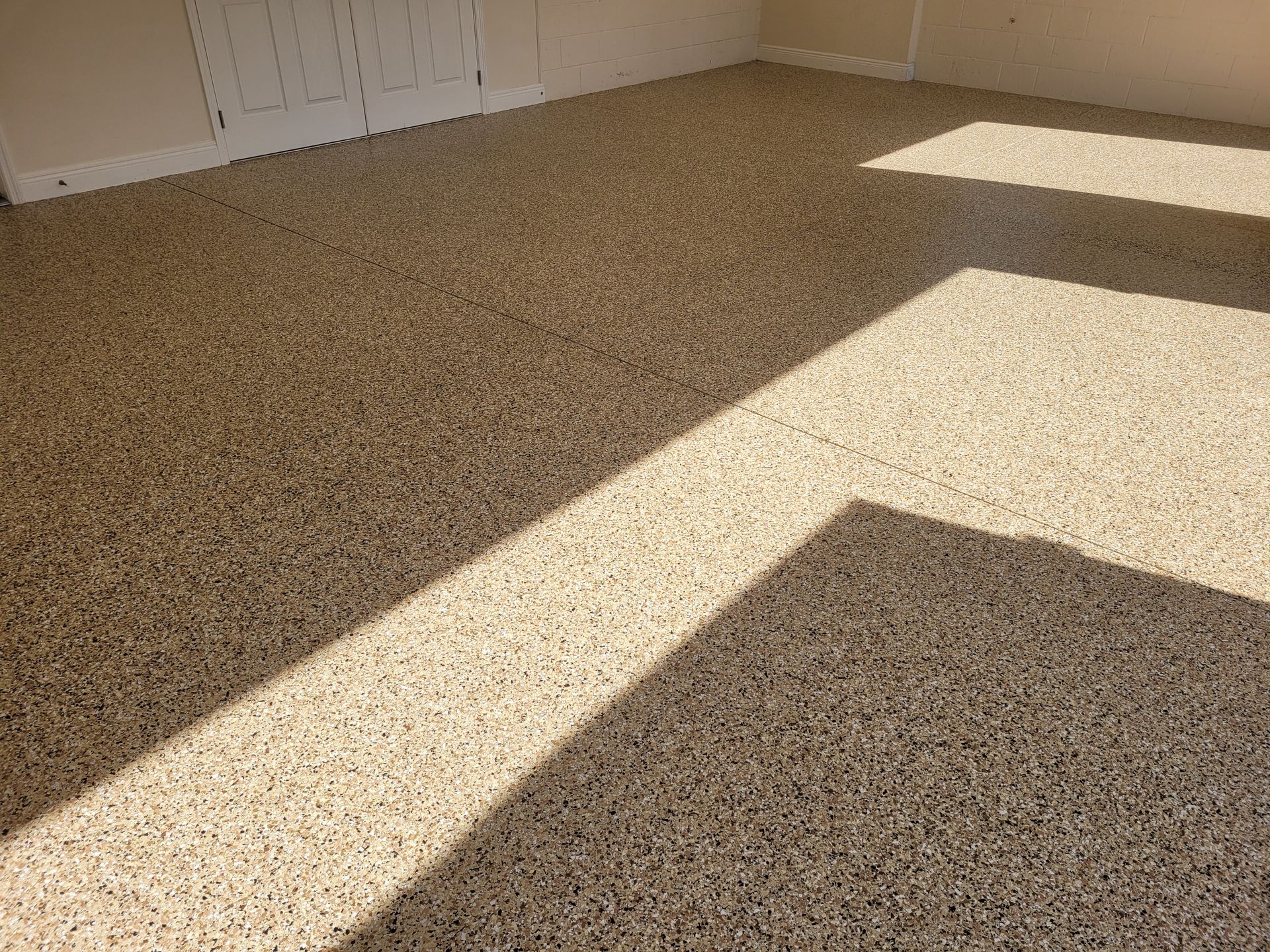 Beige speckled epoxy floor with sunlight shadows.