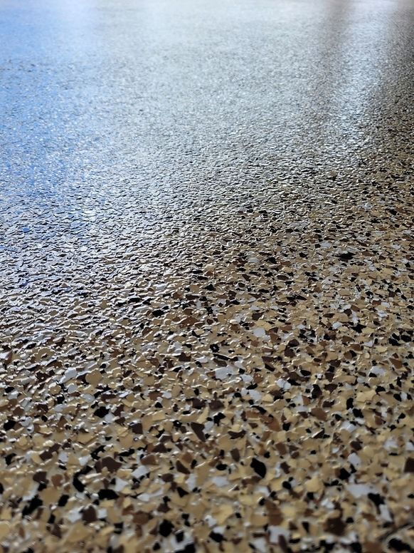 Close-up of a speckled, glossy floor. The floor has flecks of beige, brown, and white.