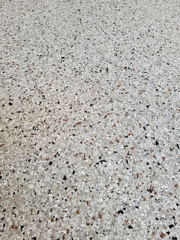Terrazzo flooring with speckled pattern in shades of gray, black, and brown.