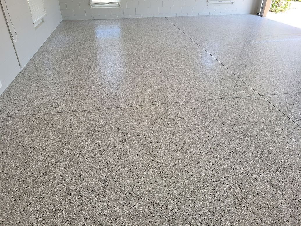 Epoxy-coated garage floor, light gray with speckled appearance; reflective, bright, clean.